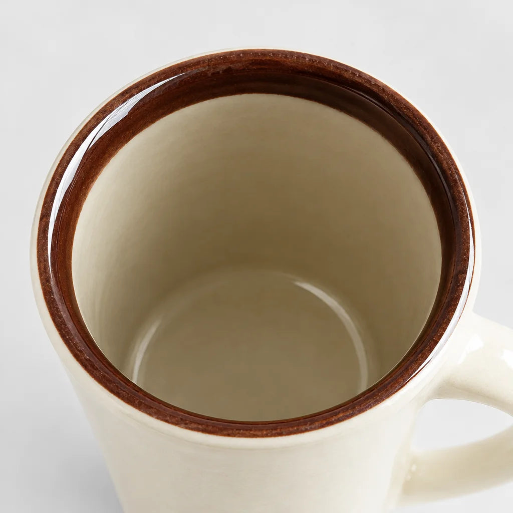 A close overhead macro of the exact beige mini-pot mug's opening, emphasizing the curved ceramic lip